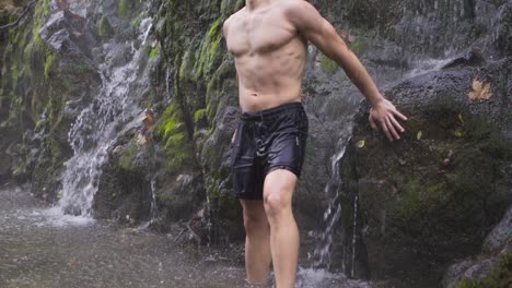 Muscular-male-getting-wet-under-waterfall.-Slow-motion.